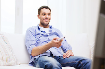 Image showing smiling man with tv remote control at home