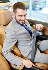 Image showing happy man sitting in car at auto show or salon