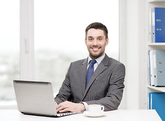 Image showing smiling businessman with laptop and coffee