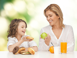 Image showing happy mother and daughter eating breakfast