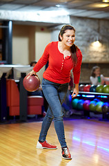 Image showing happy young woman throwing ball in bowling club