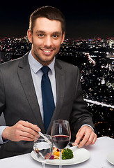 Image showing smiling man eating main course