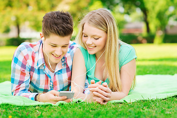 Image showing smiling couple with smartphone and earphones