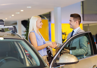 Image showing happy woman with car dealer in auto show or salon