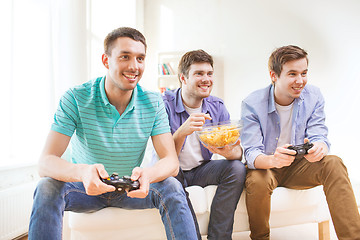 Image showing smiling friends playing video games at home