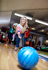 Image showing happy young woman throwing ball in bowling club