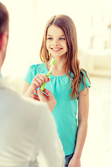 Image showing male doctor giving toothbrush to smiling girl
