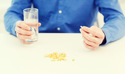 Image showing male hand holding pill and glass of water