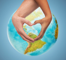 Image showing human hands showing heart shape over earth globe