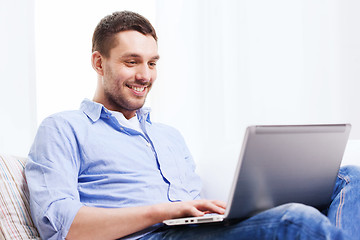 Image showing smiling man working with laptop at home