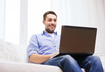 Image showing smiling man working with laptop at home