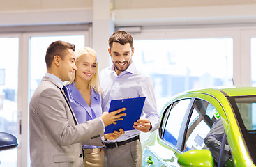 Image showing happy couple with car dealer in auto show or salon