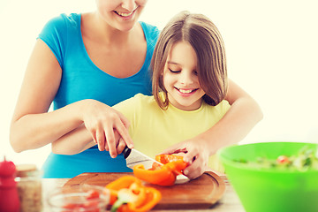 Image showing smiling little girl with mother chopping pepper