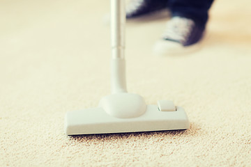 Image showing close up of male hoovering carpet
