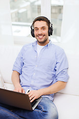 Image showing smiling man with laptop and headphones at home