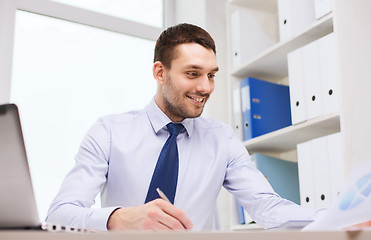 Image showing businessman with laptop and papers in office