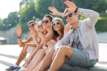 Image showing group of smiling friends sitting on city street