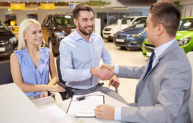 Image showing happy couple with car dealer in auto show or salon