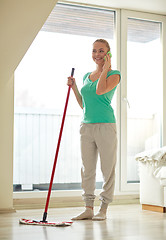 Image showing happy woman with smartphone mopping floor at home