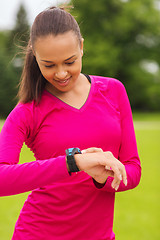 Image showing smiling young woman with heart rate watch