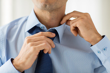 Image showing close up of man in shirt adjusting tie on neck