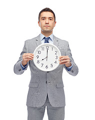 Image showing businessman in suit holding clock with 8 o'clock