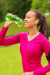 Image showing smiling woman with player drinking from bottle