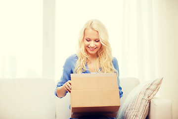 Image showing smiling young woman opening cardboard box