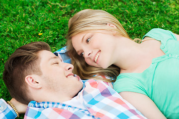 Image showing smiling couple lying on grass in park