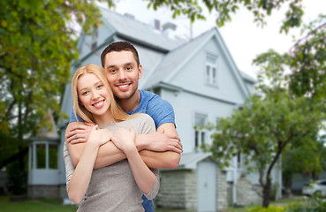 Image showing smiling couple hugging over house background