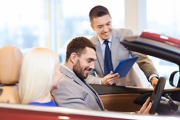 Image showing happy couple with car dealer in auto show or salon