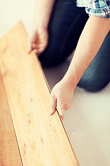 Image showing close up of male hands intalling wood flooring