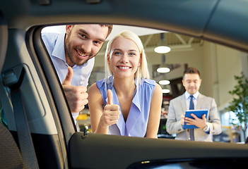 Image showing happy couple with car dealer in auto show or salon