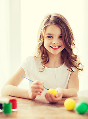Image showing smiling little girl coloring eggs for easter