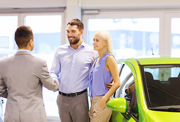 Image showing happy couple with car dealer in auto show or salon