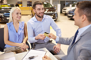 Image showing happy couple with car dealer in auto show or salon