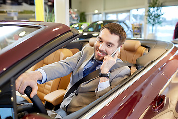 Image showing happy man sitting in car at auto show or salon