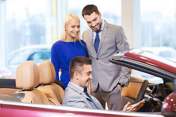 Image showing happy couple with car dealer in auto show or salon