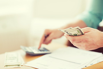 Image showing close up of man counting money and making notes