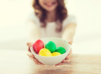 Image showing close up of girl holding bowl with colored eggs