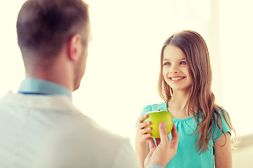 Image showing male doctor giving an apple to smiling little girl