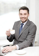 Image showing smiling businessman with laptop and coffee