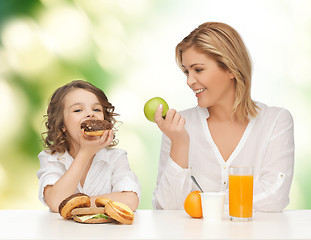 Image showing happy mother and daughter eating breakfast