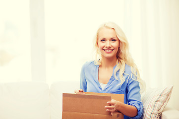 Image showing smiling young woman opening cardboard box