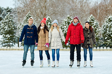 Image showing happy friends ice skating on rink outdoors