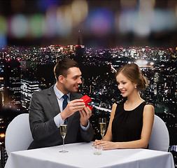 Image showing excited young woman looking at boyfriend with box