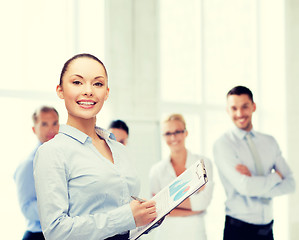 Image showing young smiling businesswoman with clipboard and pen