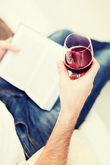 Image showing male hand holdind book and glass of red wine