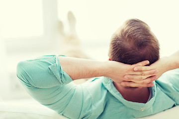 Image showing man lying or sitting on sofa at home from back