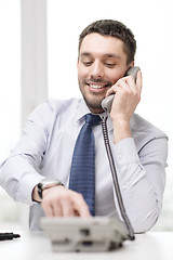 Image showing smiling businessman with telephone dialing number